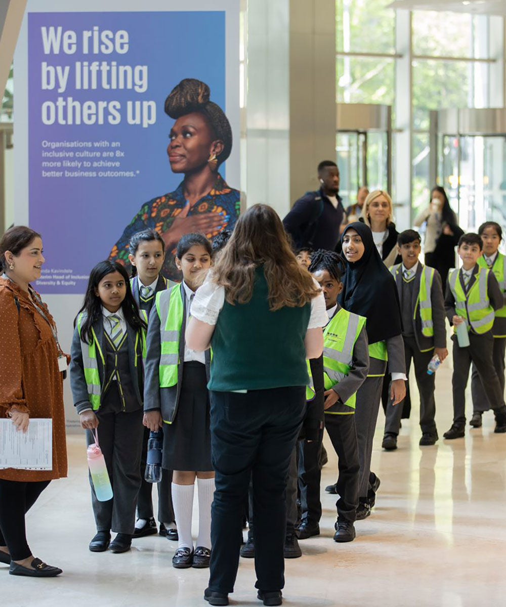 A staff member guiding children through a KPMG in the UK office