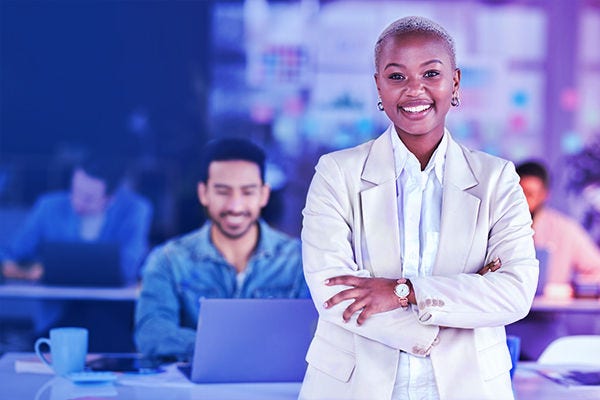 Smiling black woman with her arms crossed in an office setting.