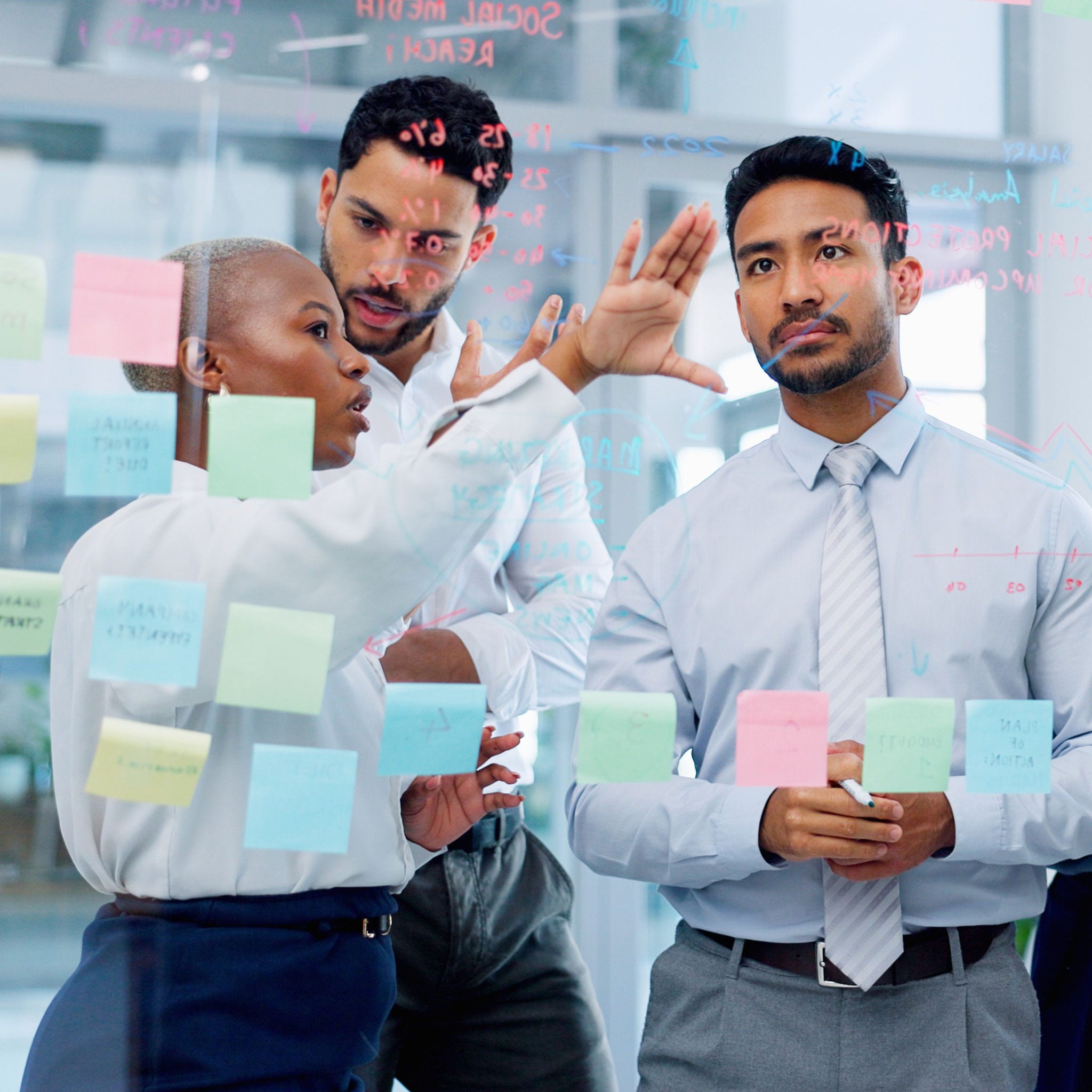 Meeting, collaboration and sticky notes with a business man training a team while planning strategy on glass in an office. Teamwork, diversity and workshop with a man and woman employee group at work