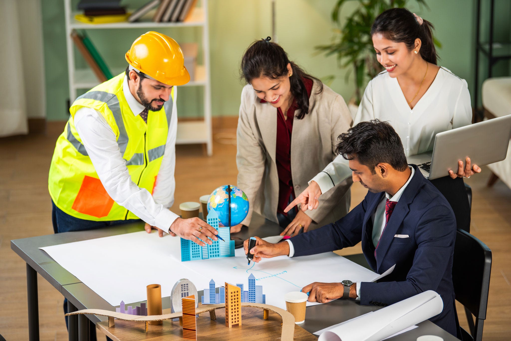 Indian asian Architect, builder and engineer meeting together and discussing city planning on table