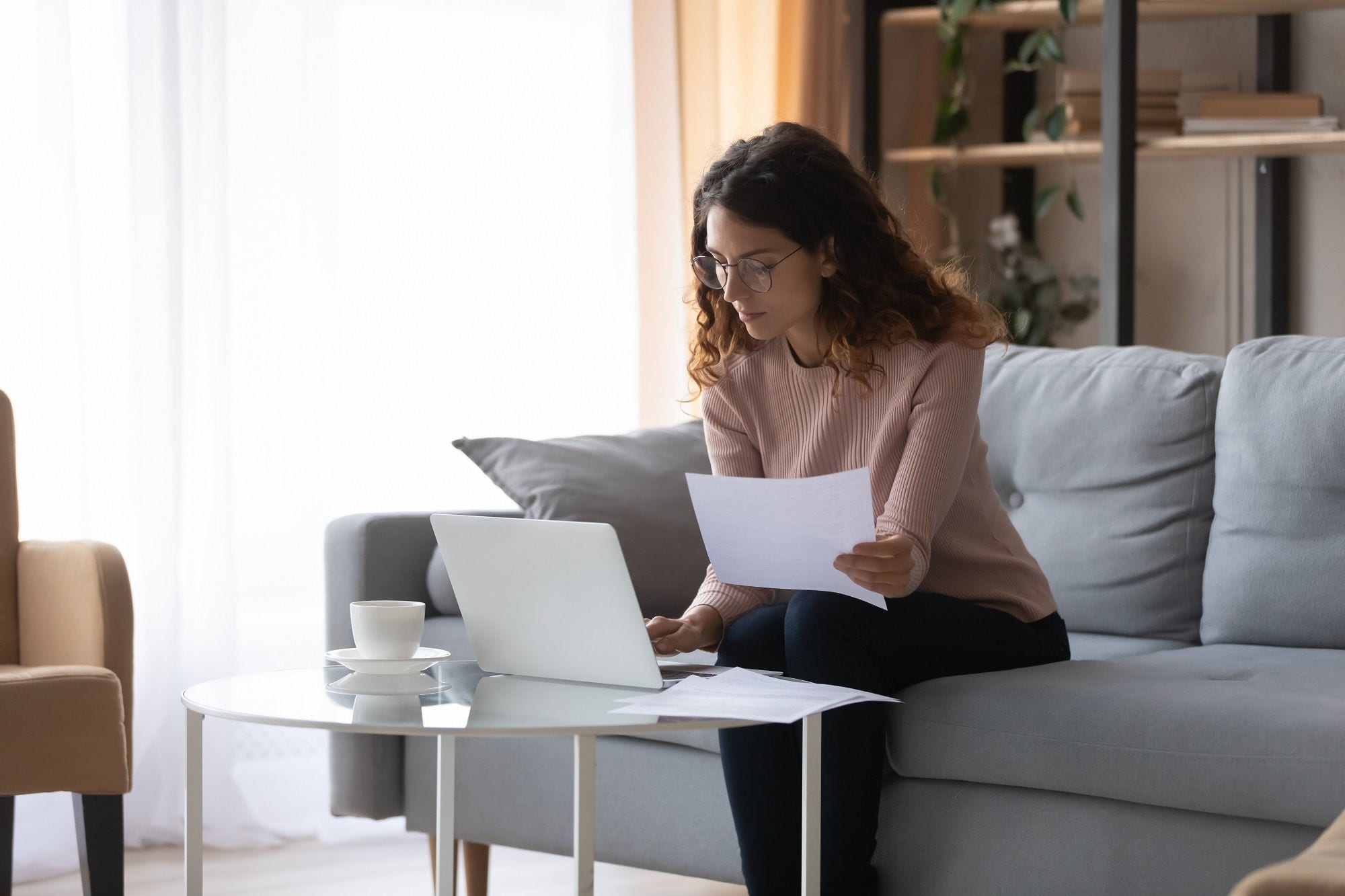 Woman holding a paper and working on her laptop