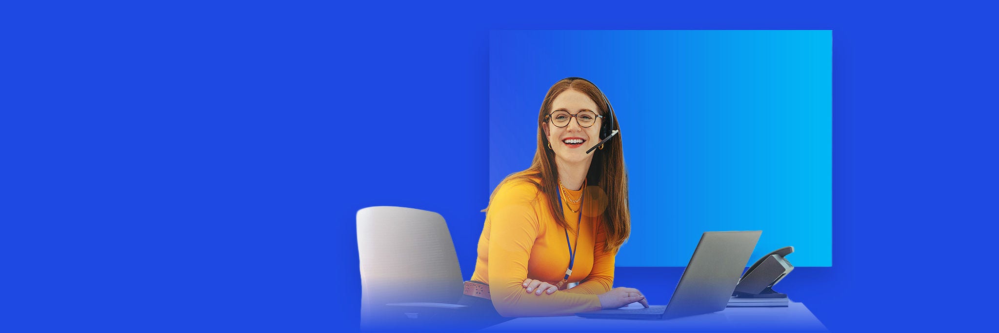 Person wearing a headset seated at a desk, using a laptop, against a blue background