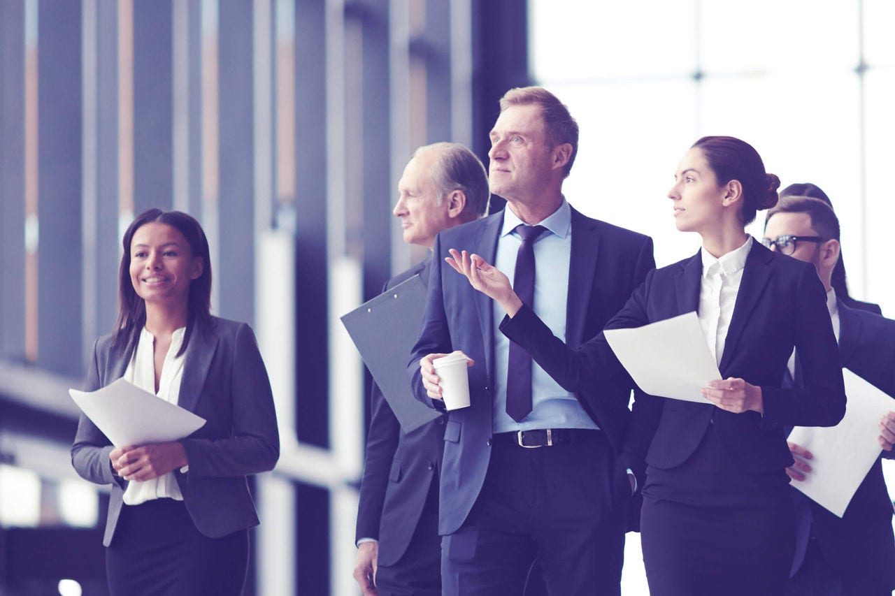 A group of professionals walking together, exchanging ideas and carrying documents.