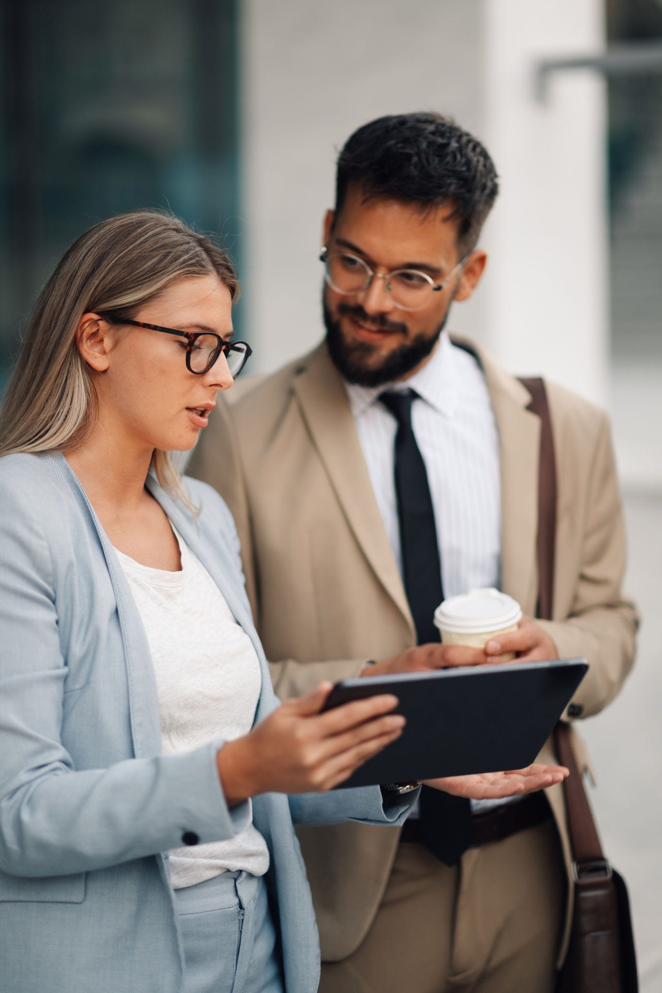 2180092793 Businesswoman holding digital tablet having informal meeting with her male colleague outdoors. They are discussing new business opportunities