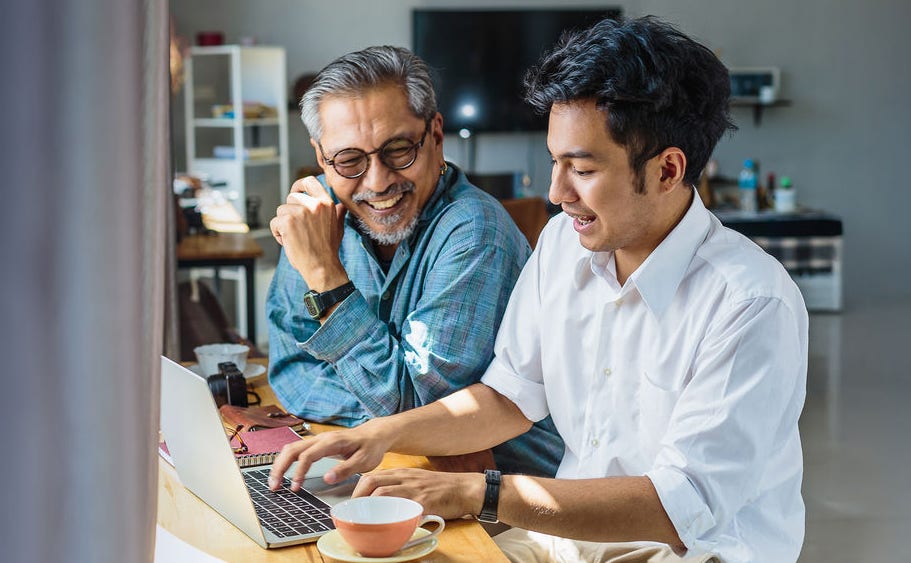 Father and adult son work on a laptop computer