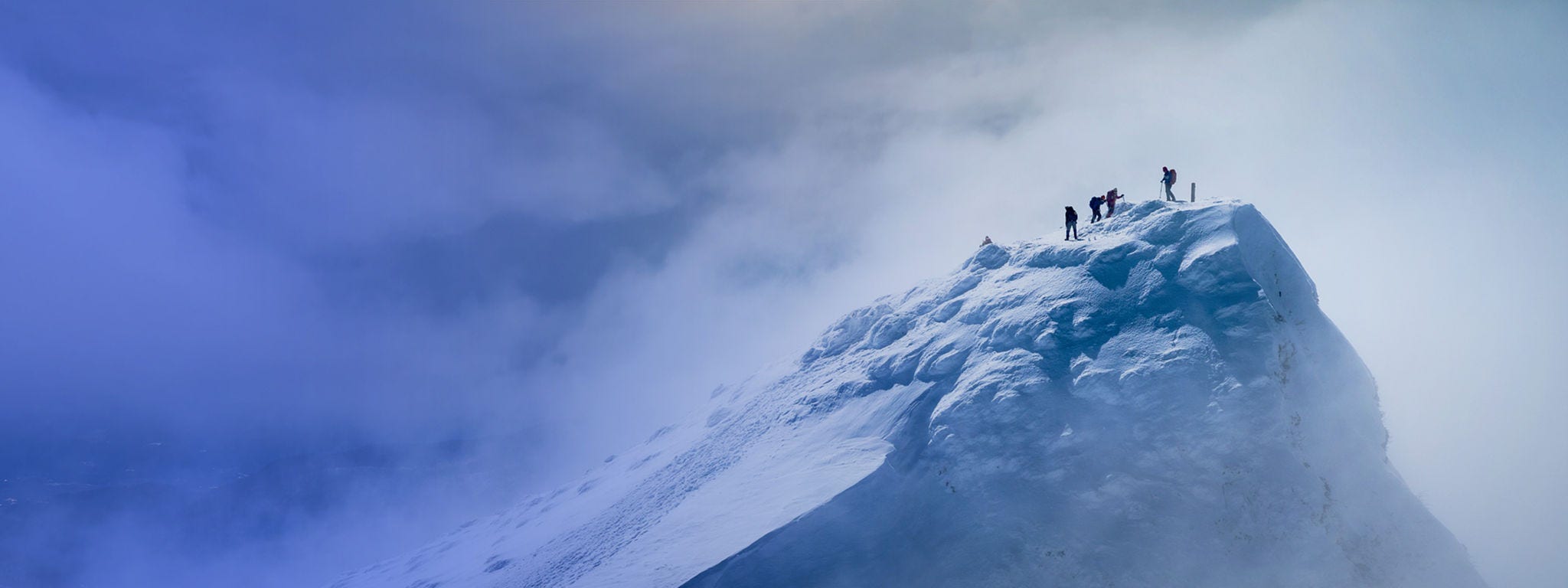 People on top of a snow-capped mountain high up in the clouds