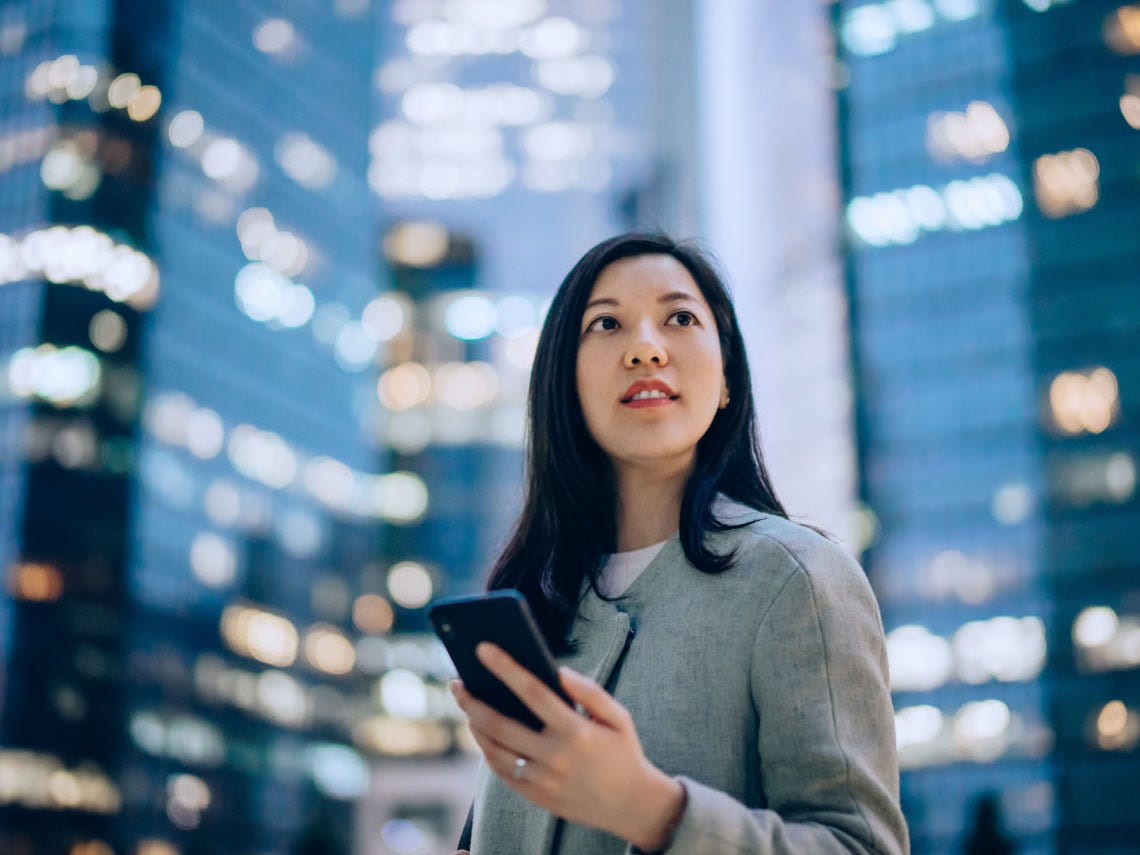 Business woman holding phone in front of skyscrapers Business woman holding phone in front of skyscrapers