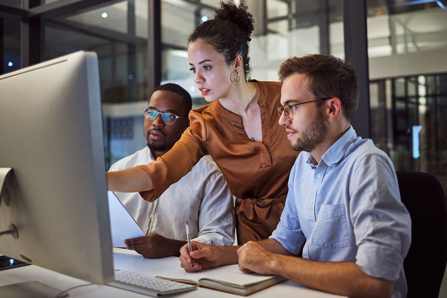 Two man and a woman looking at desktop