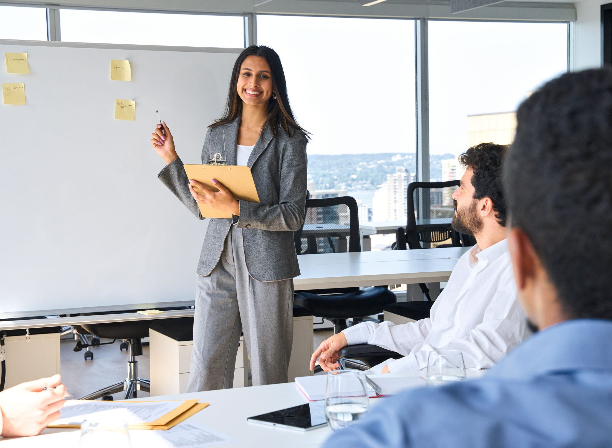 Happy Indian business woman professional presenter giving presentation at corporate group meeting in office. Busy diverse team business people working on corporate strategy on conference training.