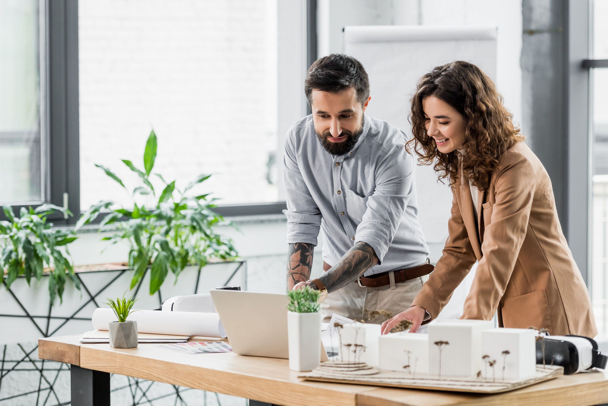 smiling virtual reality architects looking at laptop in office