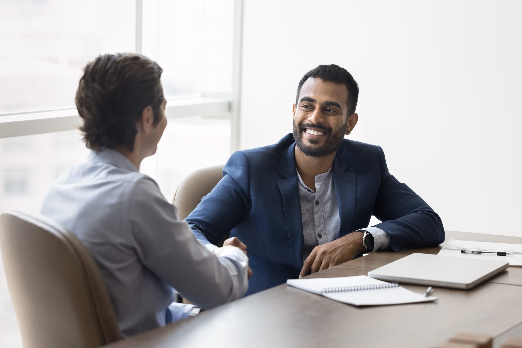 Happy Indian business owner man shaking hands with male partner
