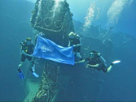 Three people underwater scuba diving holding a sign that says Scuba Diving Club