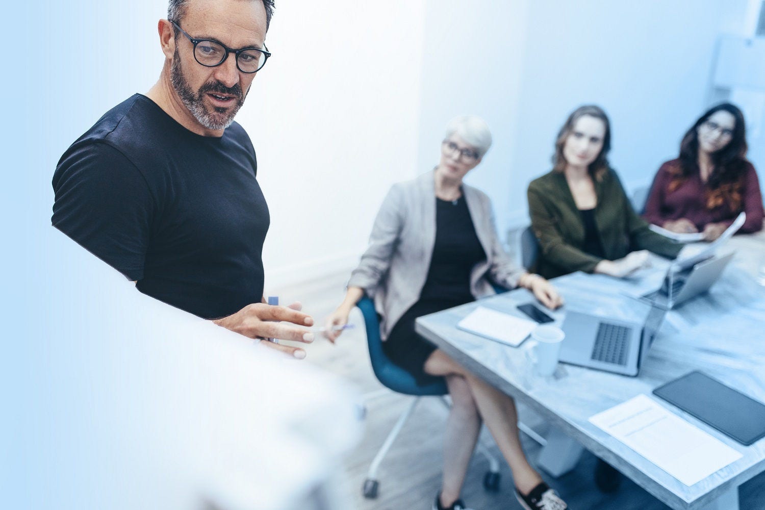 Businessman giving presentation on white board to colleagues in conference room. Entrepreneur doing presentation in meeting room.