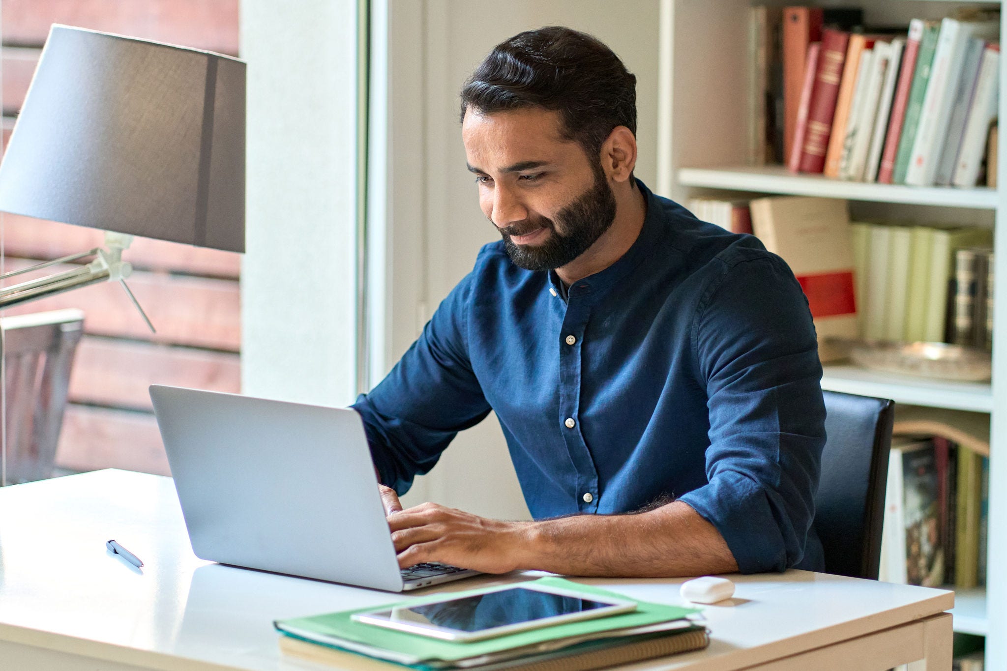 Indian business man remote working on laptop computer sitting at home office. Programme highlights