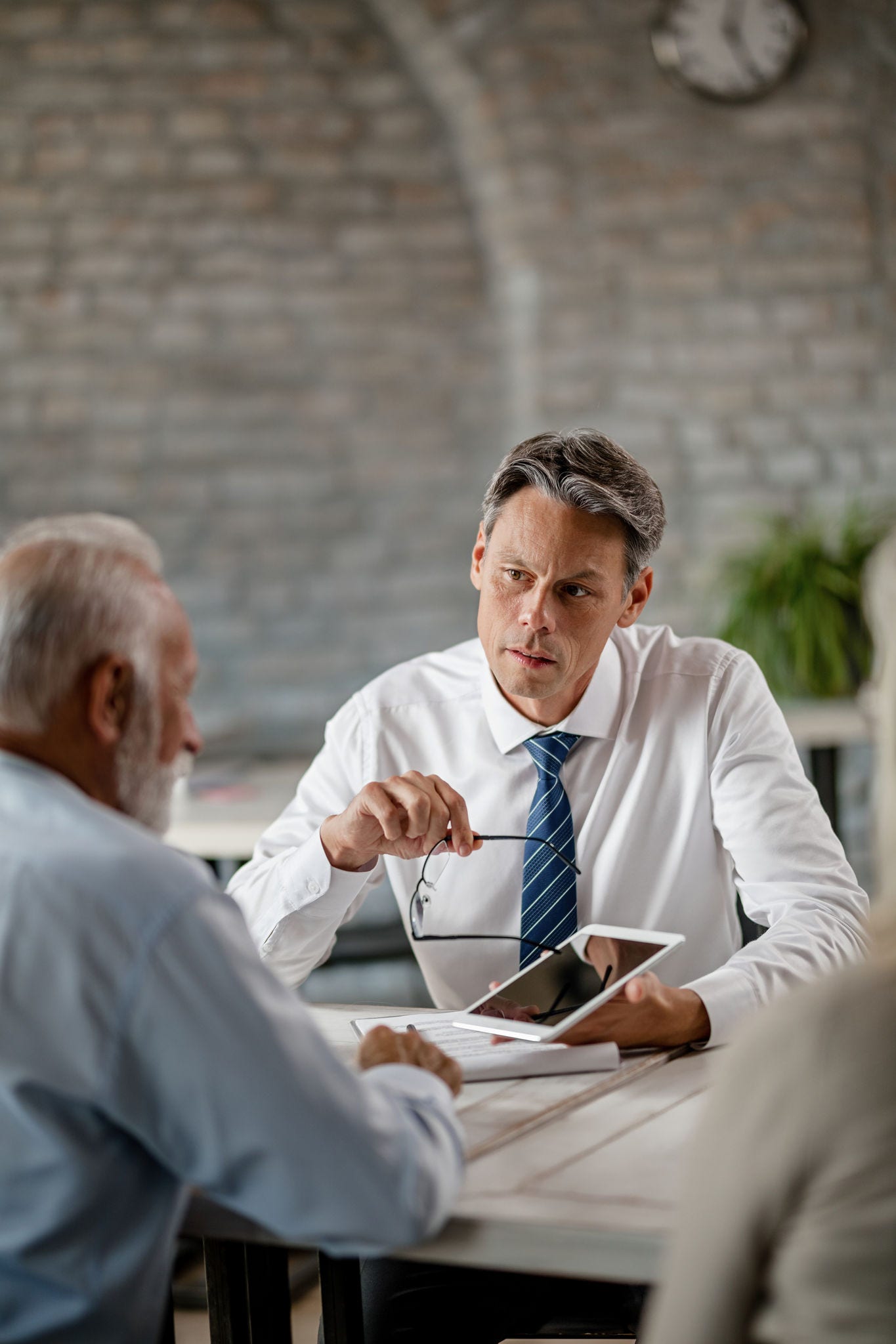 Insurance agent communicating with senior clients while showing the something on a touchpad during a meeting in the office.