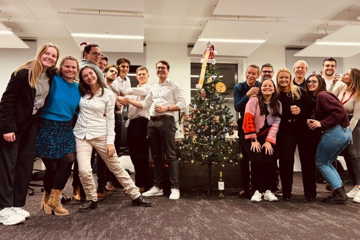 A group of people next to the Christmas tree in the office.