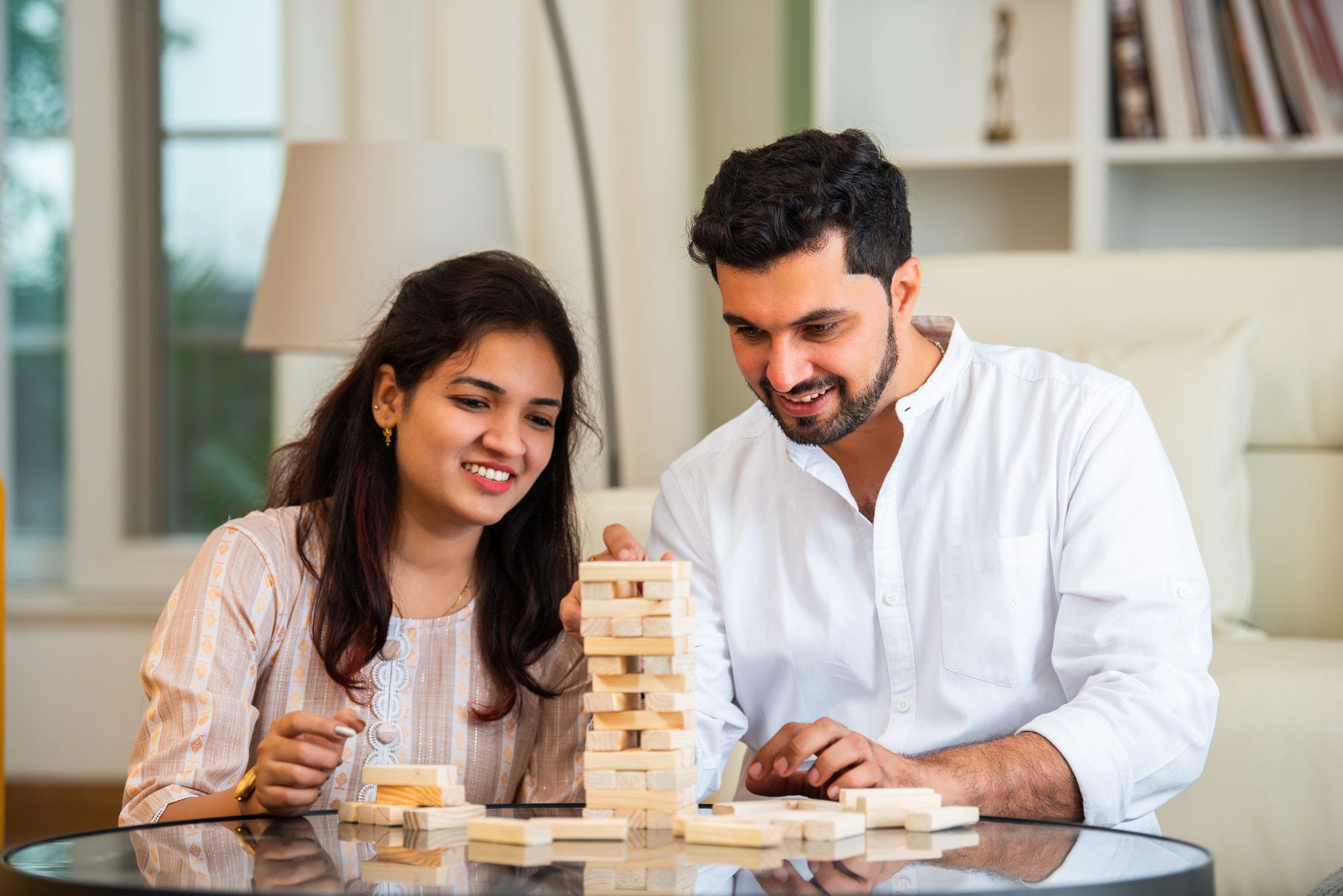 Indian young married couple playing jenga table game at home having fun