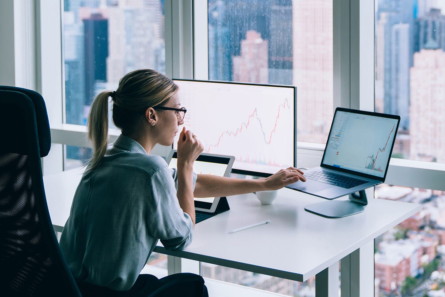 Woman viewing data on two computers in an office