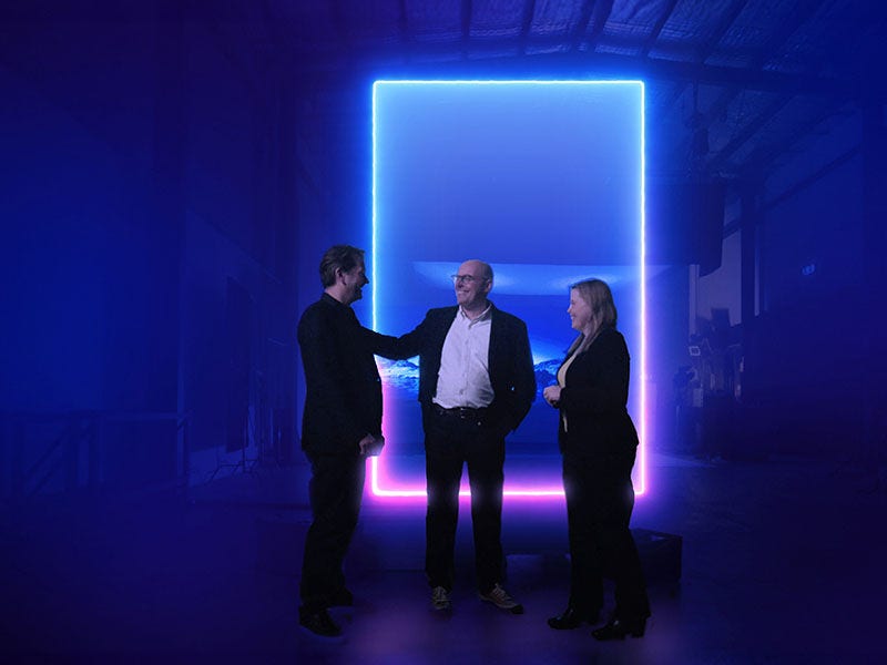KPMG colleagues having discussion in front of glowing blue-pink frame KPMG colleagues having discussion in front of glowing blue-pink frame