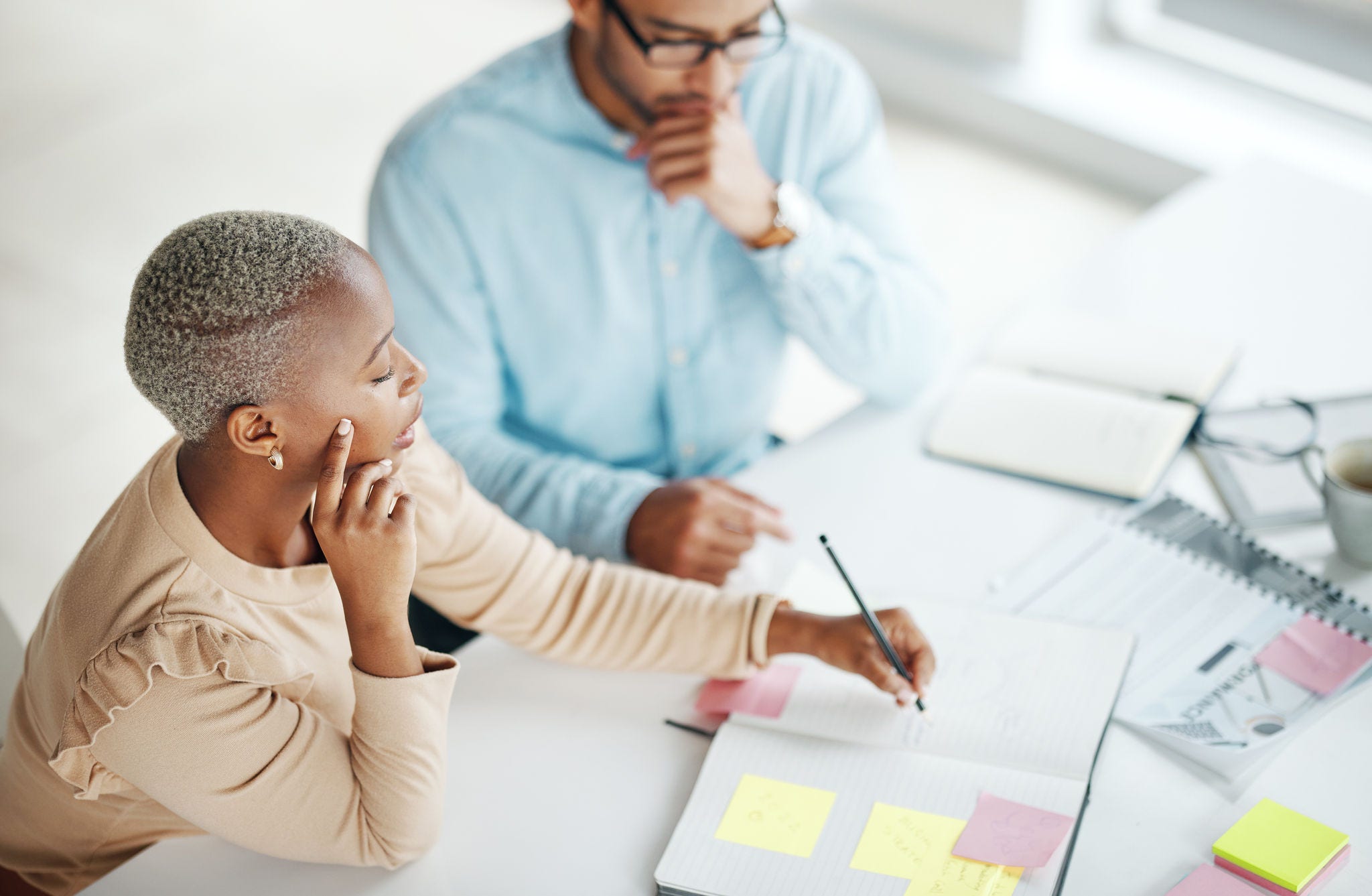 Collaboration, strategy overhead and a business black woman at work with a man colleague in an office. Teamwork, planning and documents with professional people brainstorm thinking while working Collaboration, strategy overhead and a business black woman at work with a man colleague in an office. Teamwork, planning and documents with professional people brainstorm thinking while working.