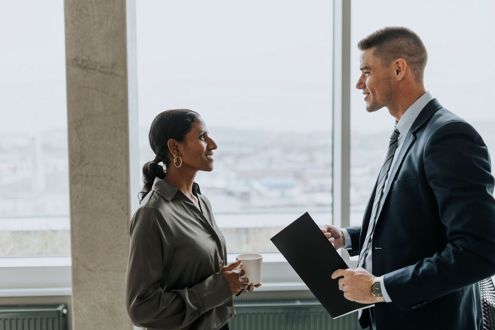 masma106435 Side view of smiling business colleagues with coffee cup and document standing in office