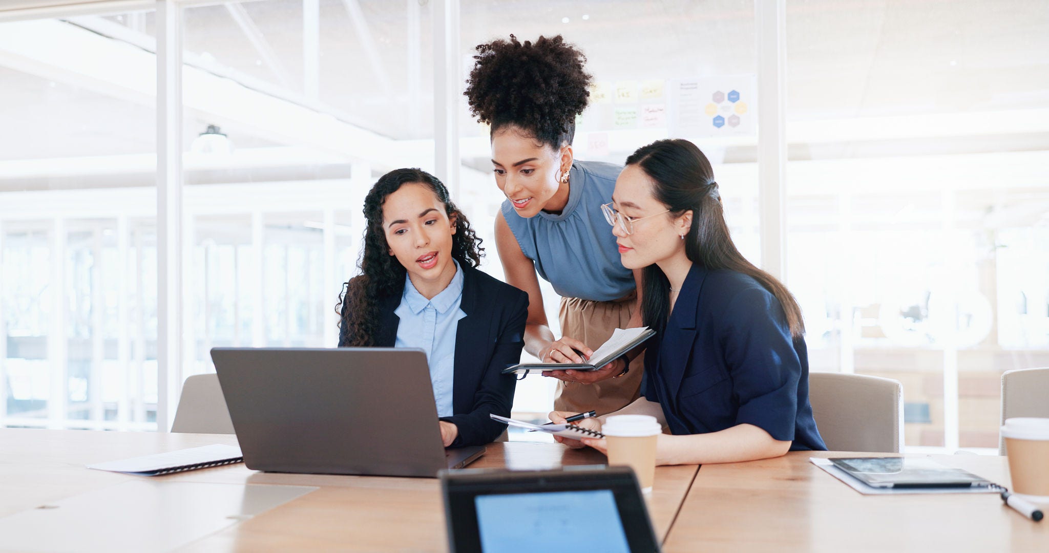 Business women, laptop and collaboration in office for marketing management, leader innovation or strategy research. Team meeting, employee support and tech manager or leadership idea discussion.