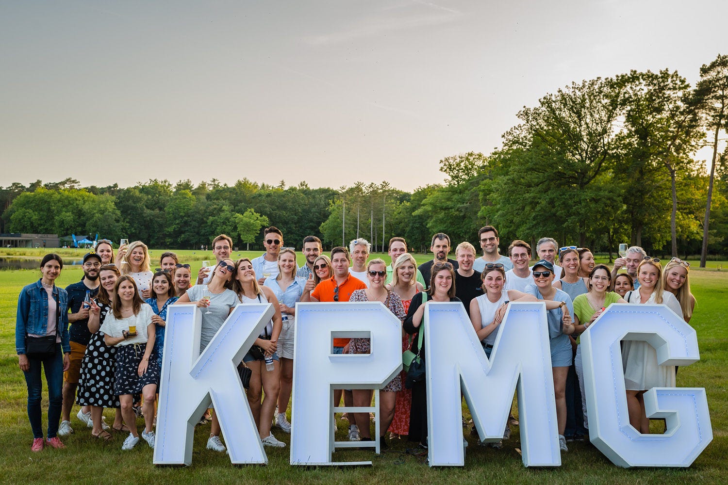 A group of people posting for the photo behind big KPMG letters.