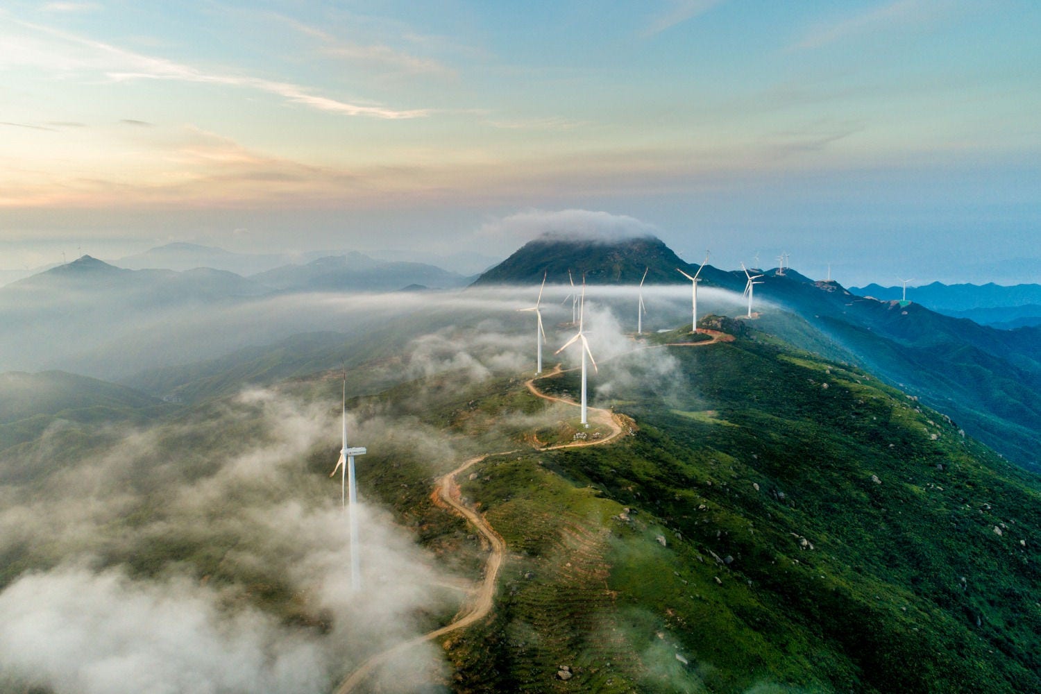 A windy road with windmills on top of a large mountain