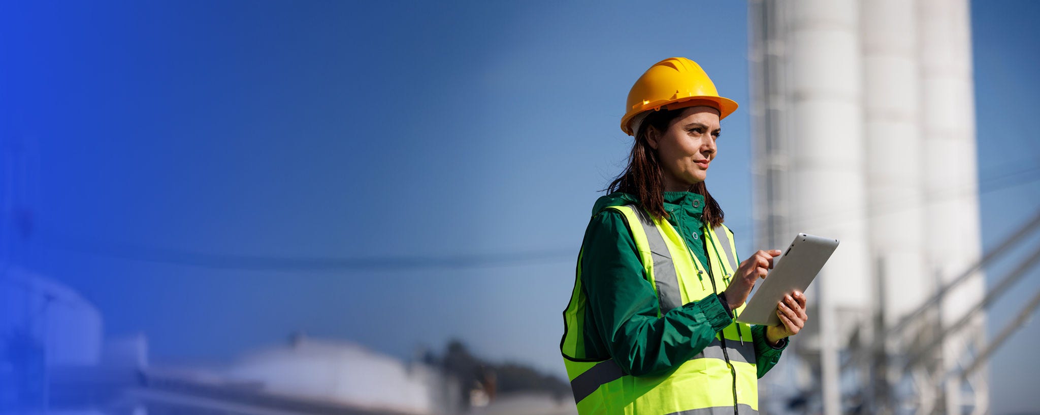 Female engineer with hardhat using digital tablet while working on construction site