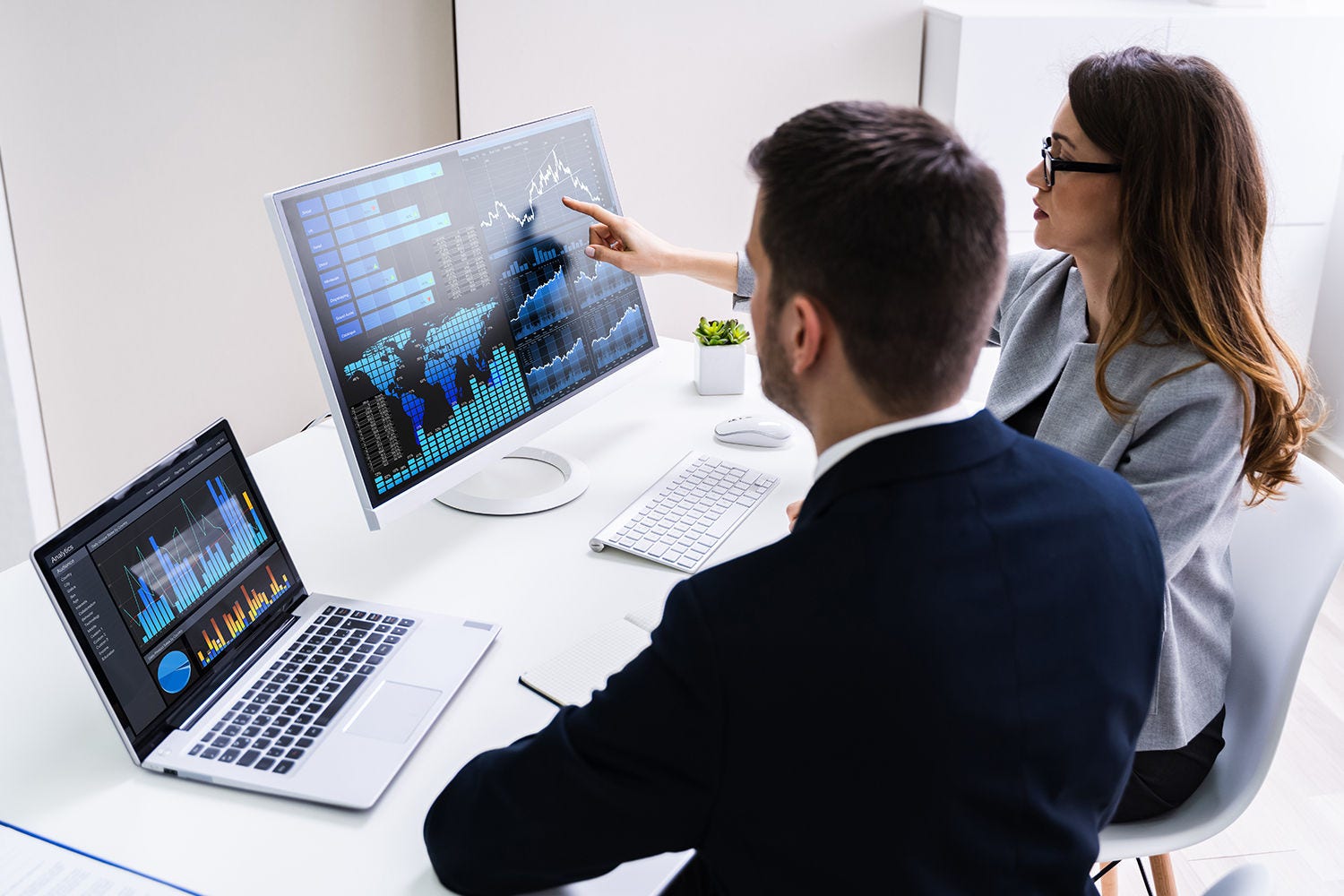Man and woman viewing data on two computers