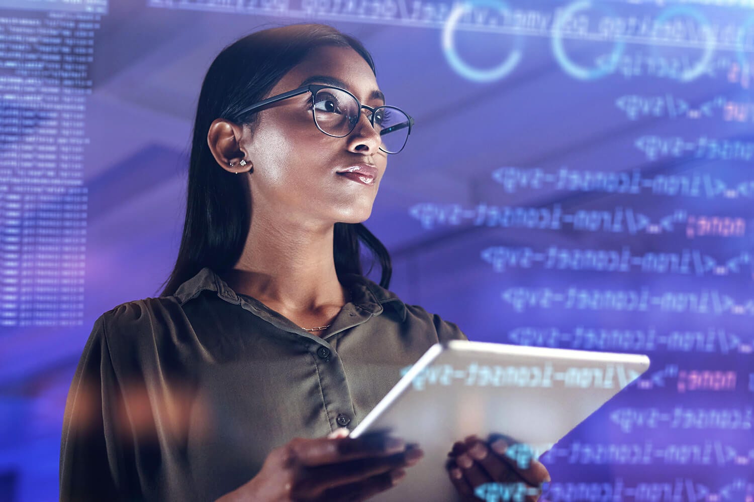 Mulher jovem a segurar um tablet, num ambiente tecnológico.