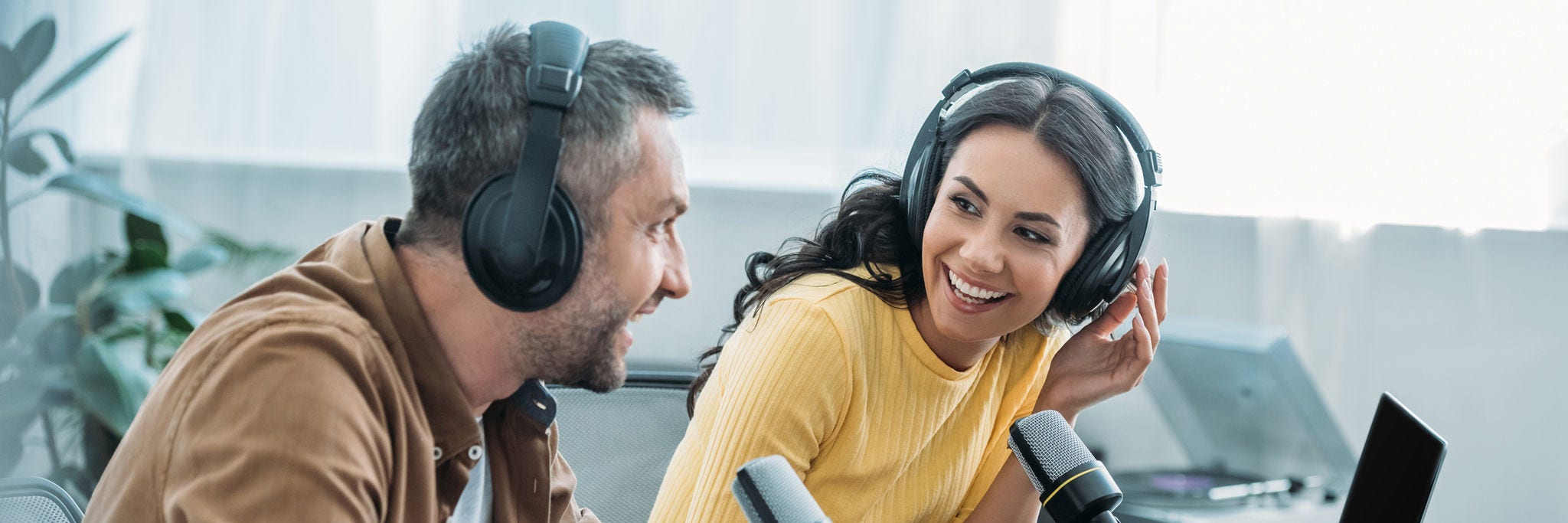 two smiling radio hosts talking while recording podcast in studio together