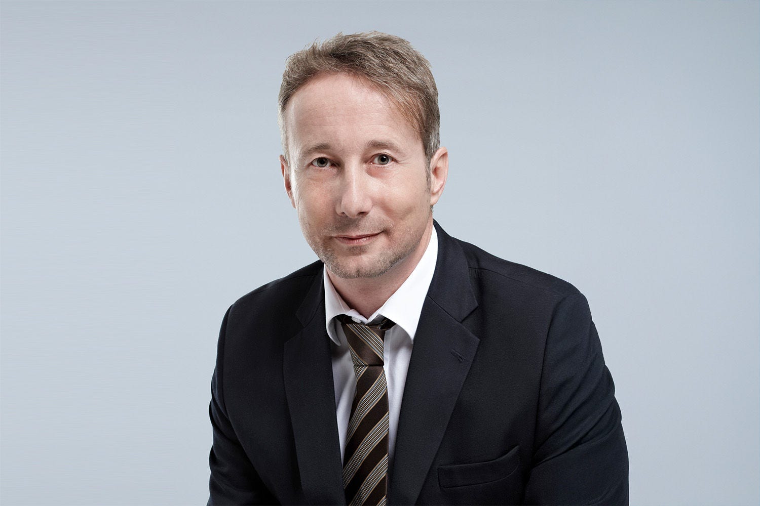 Porträt von Alfred Shubshizky vor einer hellgrauen Wand