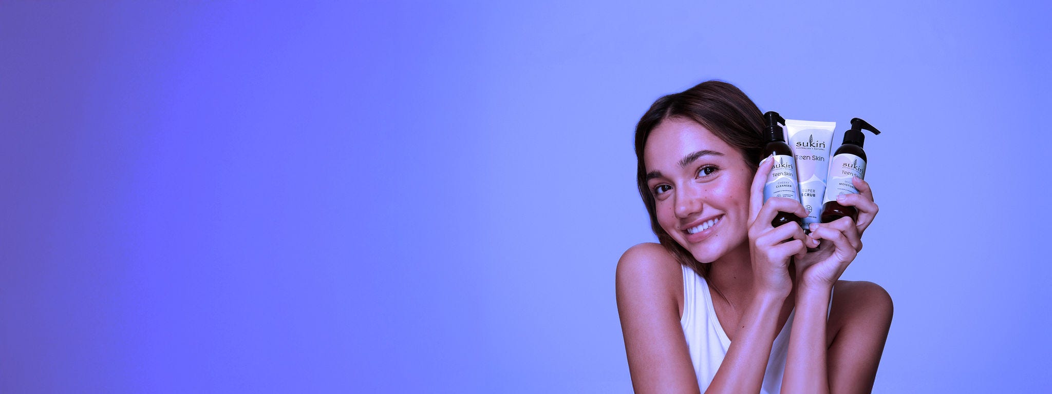 Smiling girl holding up Sukin products