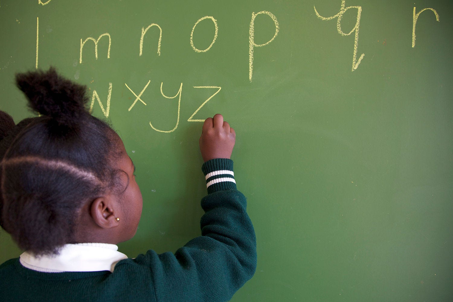 Close up shot of schoolgirl writing the alphabet on a chalkboard, KwaZulu Natal Province, South Africa
