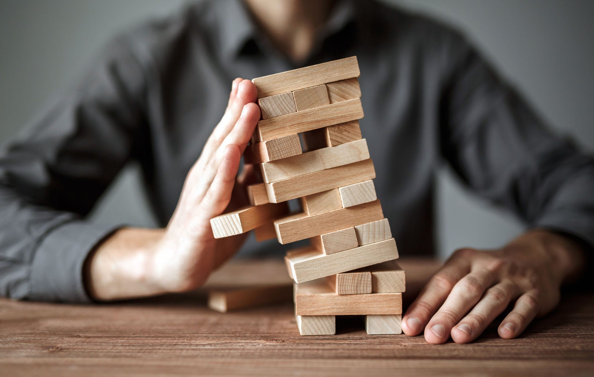 Businessman holds the model of business, made from wood blocks. Alternative risk concept, business plan and business strategy. Insurance concept.