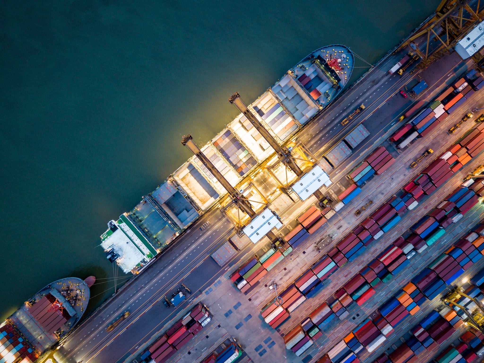 Top view of international port with Crane loading containers in import export business logistics at night. supply-chain-excellence-who-is-this-for