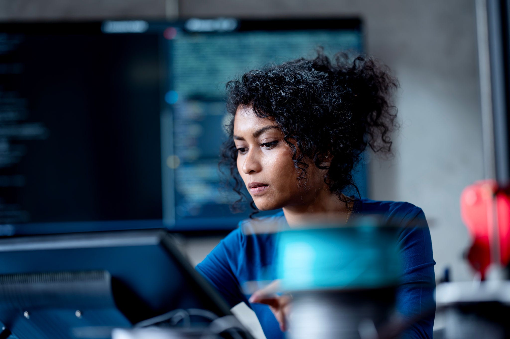 2050177197 Improve Automate Workflows and Streamline Software Testing with Machine Learning in Software Development. An Asian female software developer coding or debugging code on a computer at her desk in the tech office.