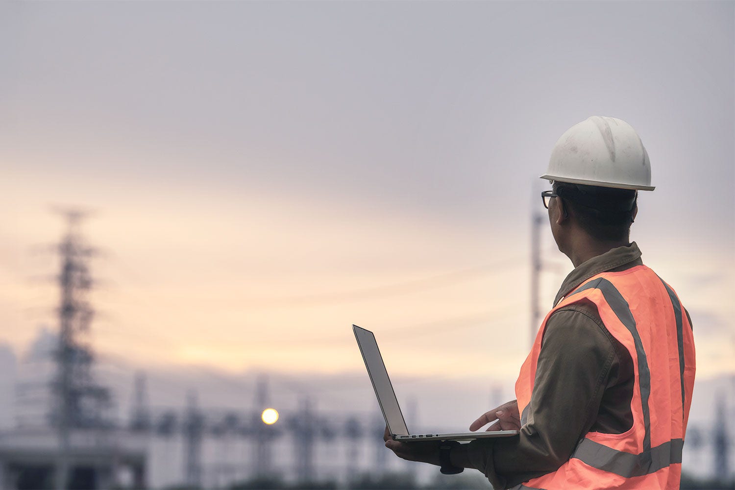 enginneer-holding-laptop-against-powerplant
