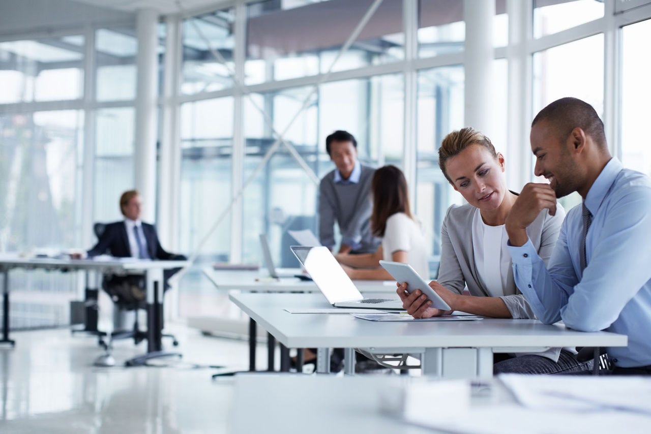 Business colleagues discussing over digital tablet at desk in office