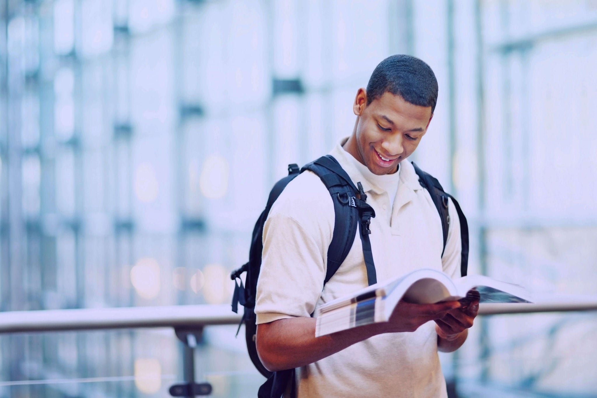 A recent graduate with a backpack on his back, reading