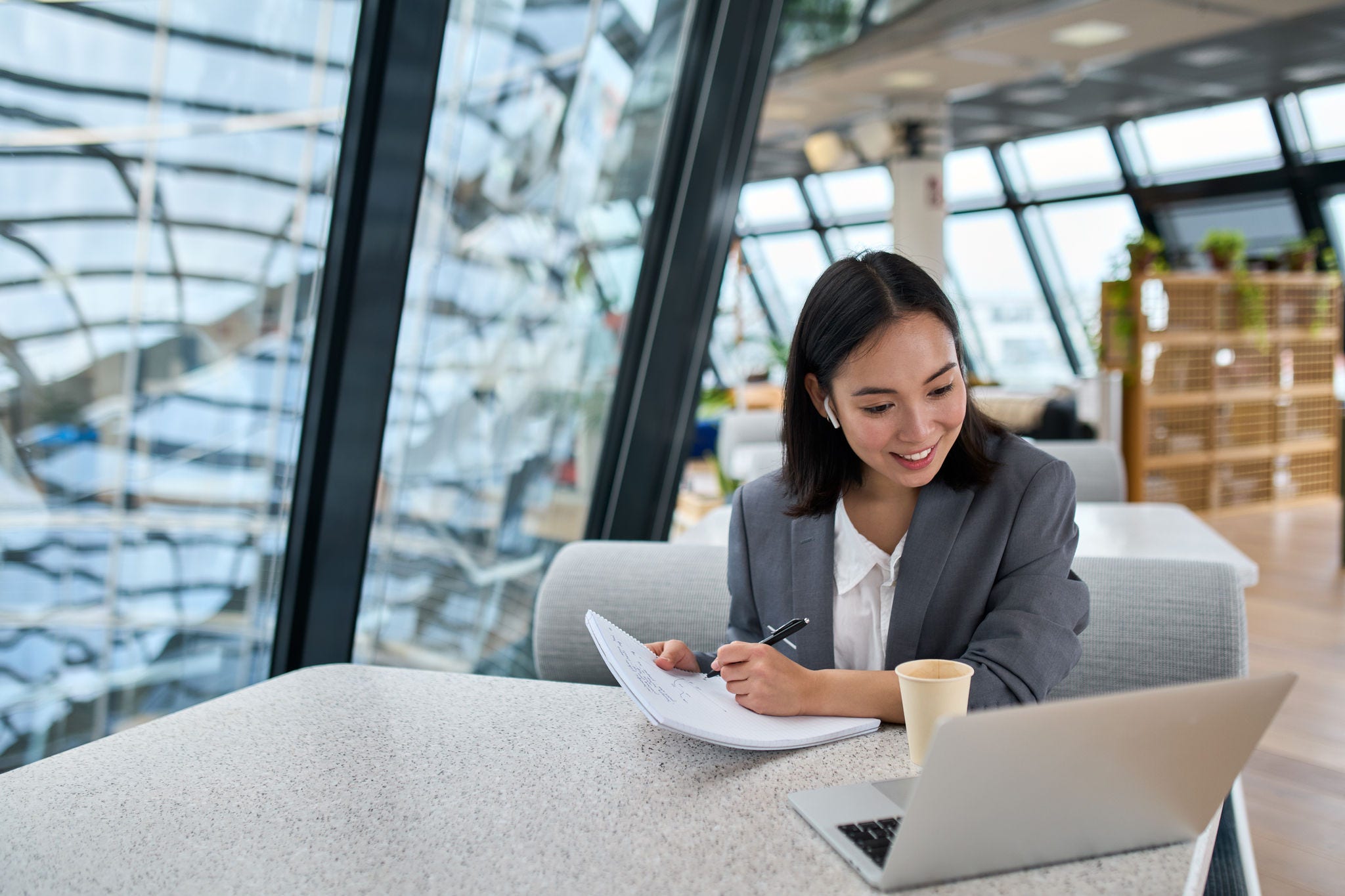 Young Asian business woman employee or executive manager using computer looking at laptop and talking leading hybrid conference remote video call virtual meeting or online interview working in office.