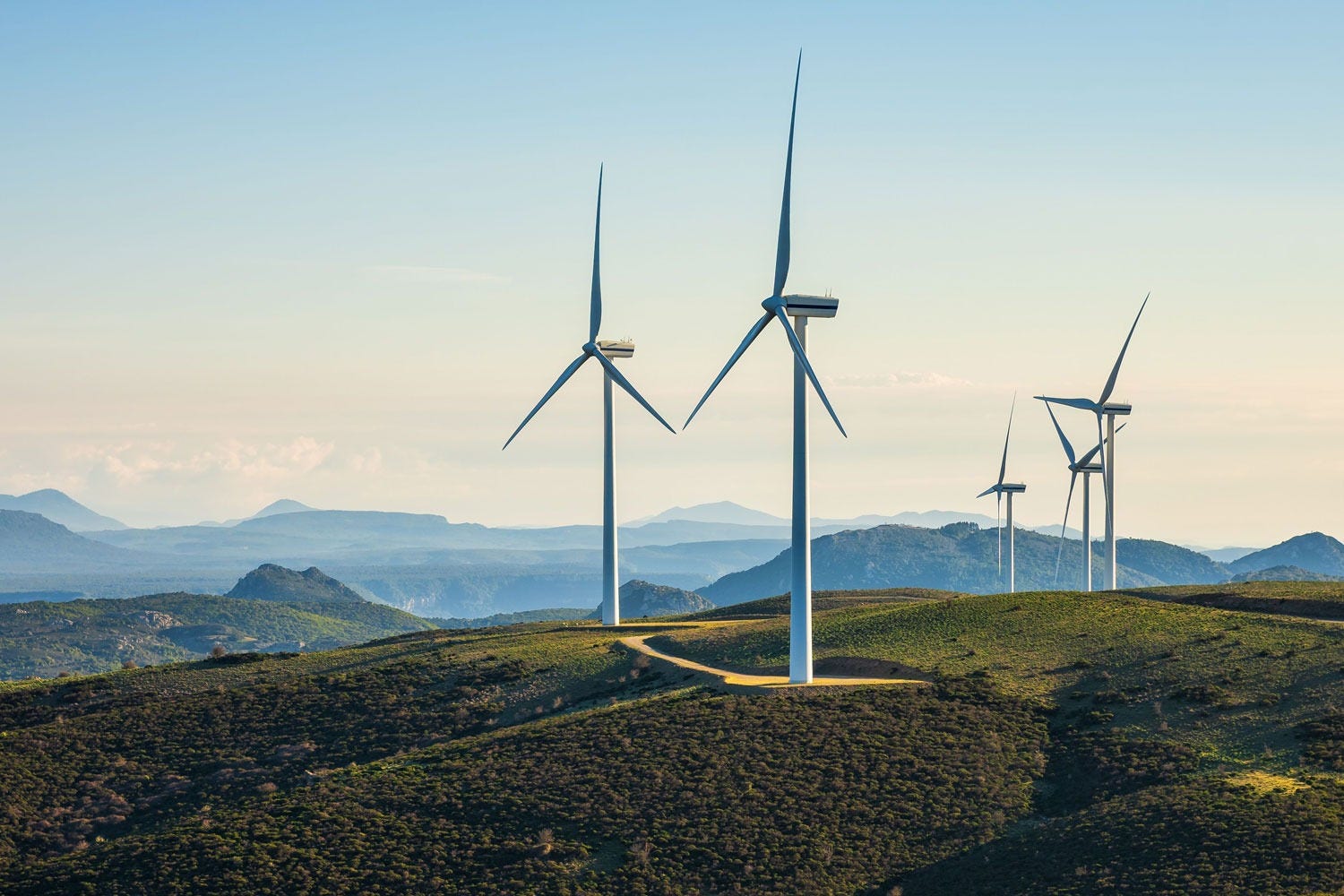 A windy dirt road with a number of windmills on top of a mountain