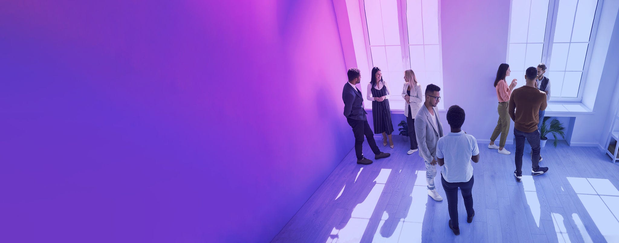 Business people in a room having a discussion Diverse people talking in groups during a meeting. High angle shot of different young community members or company employees standing in a modern office room, discussing something, sharing opinions