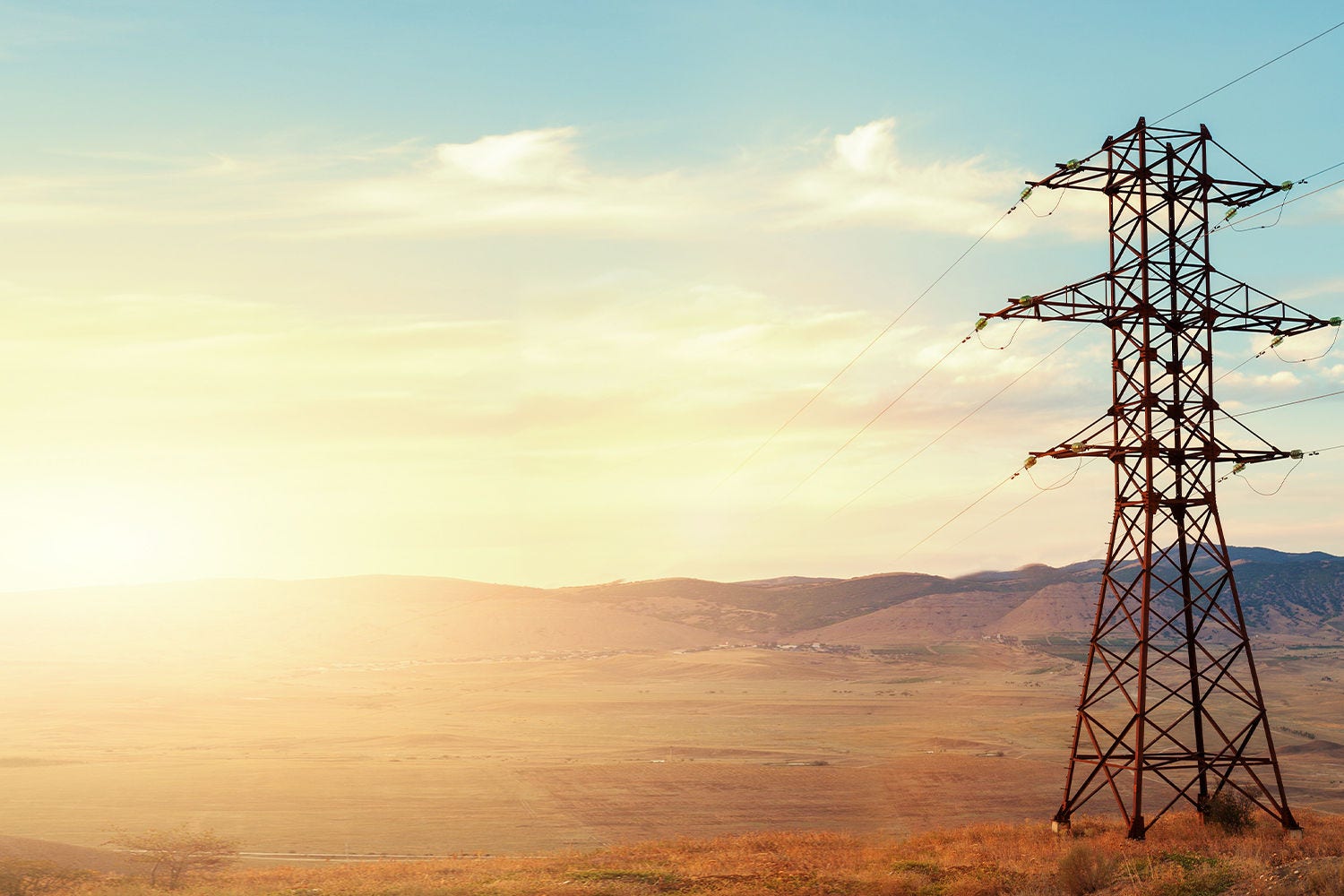 Electric power pole in field at sunset Electric power pole in field at sunset