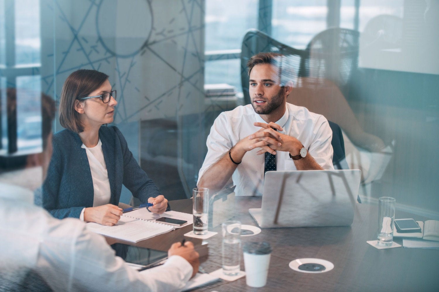 People sat at a table in an office with documents and laptops