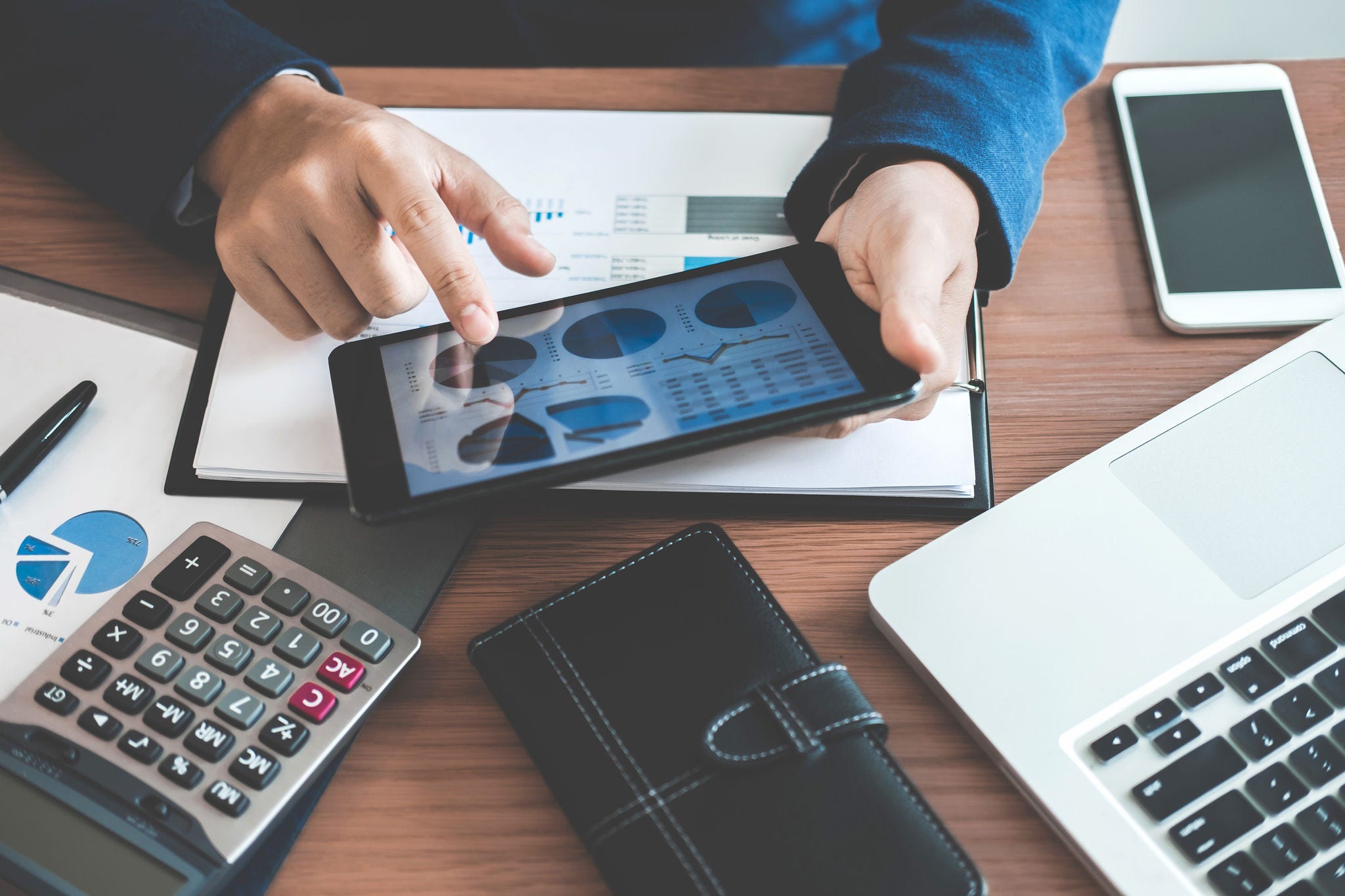 Businessman hands using text information on digital tablet to analyze financial statistical chart data and calculate cost of investment project.