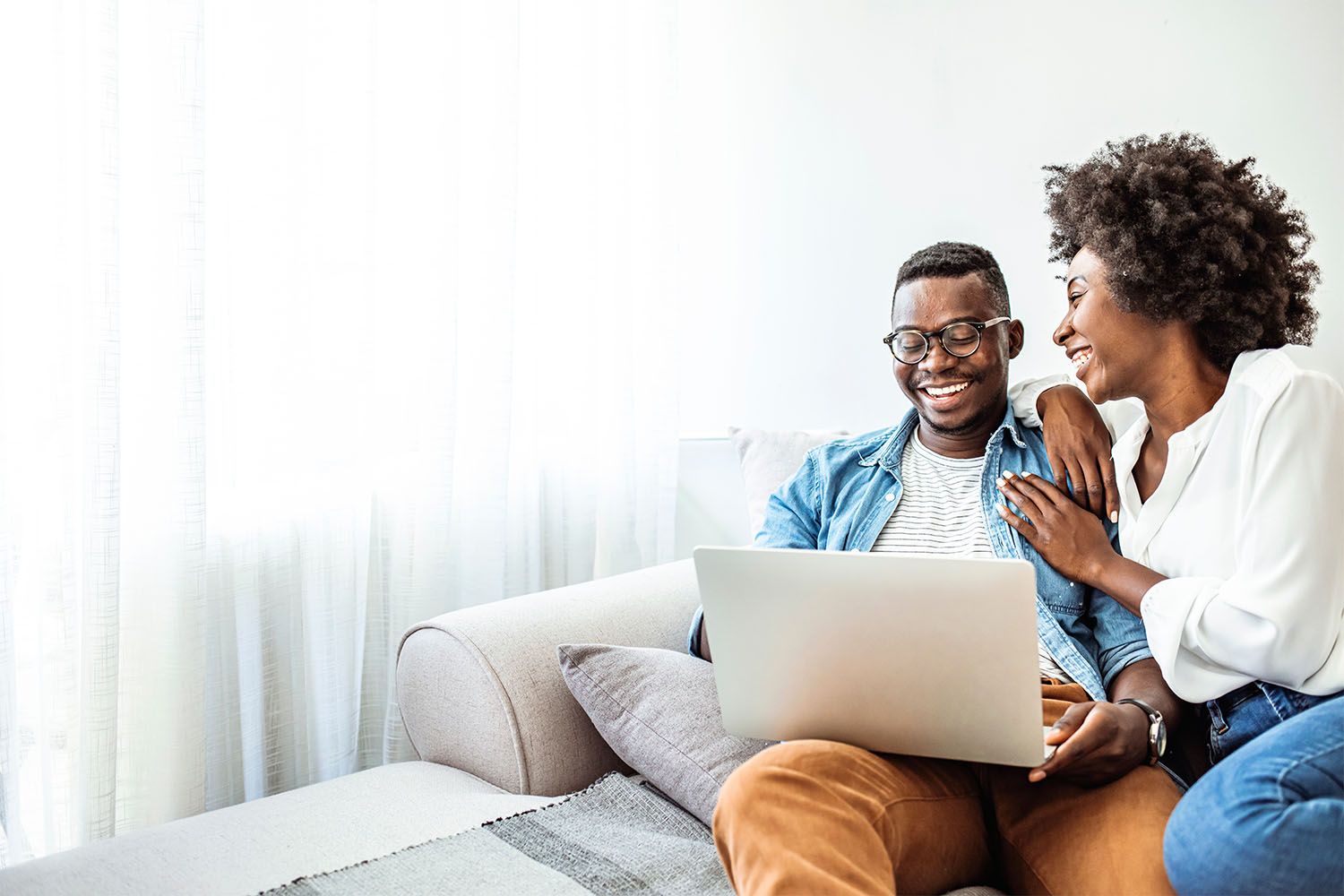 Couple laughing while looking at laptop